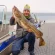 Man holding a large fish on a boat dock, Pacific fishing adventure.